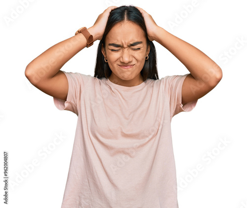 Young asian woman wearing casual clothes suffering from headache desperate and stressed because pain and migraine. hands on head.