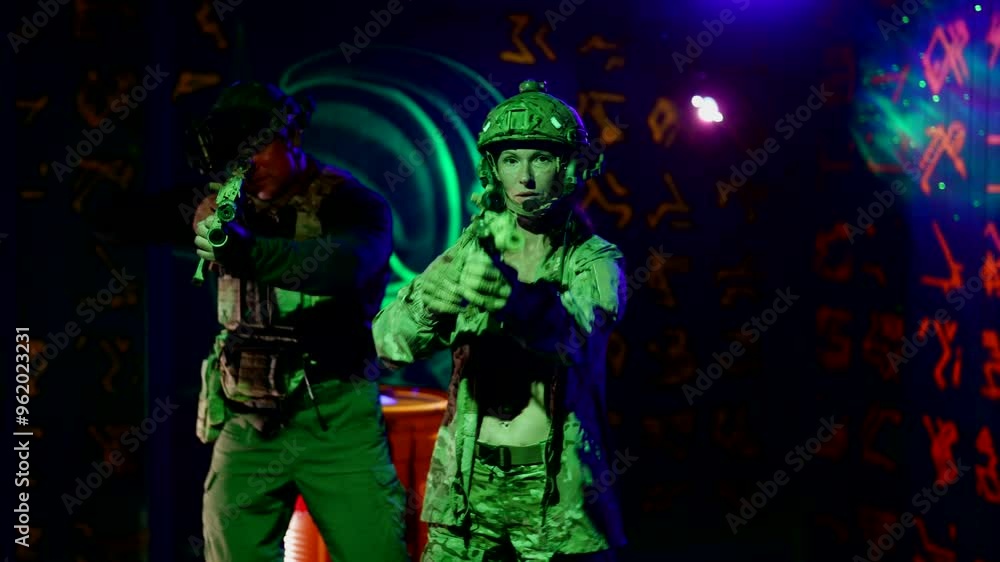 A woman dressed in a military uniform stands against a background of neon green patterns. Her look and posture express combat readiness and confidence. A woman dressed in a military uniform stands against a background of neon green patterns. Her look and posture express combat readiness and confidence.