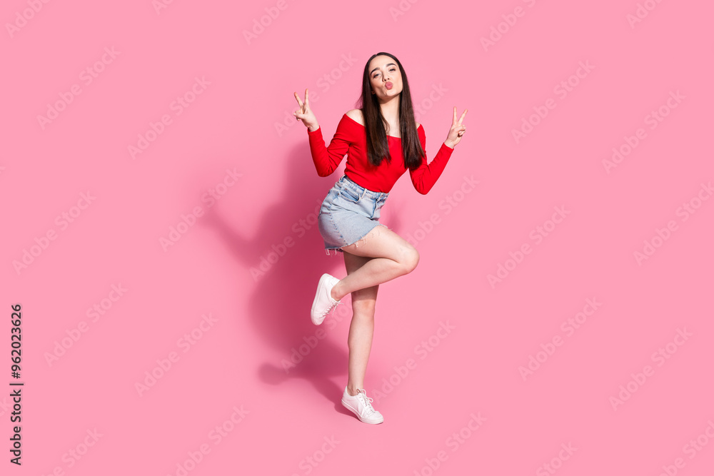 Full body portrait of pretty young girl kiss lips show v-sign isolated on pink color background Full body portrait of pretty young girl kiss lips show v-sign isolated on pink color background
