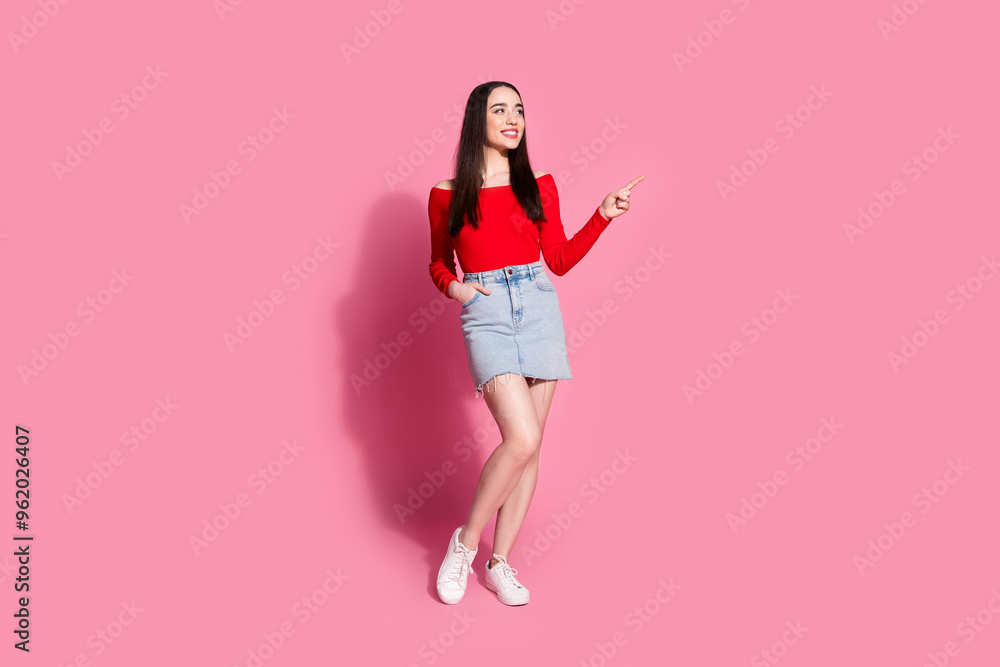 Full body portrait of pretty young girl indicate finger empty space isolated on pink color background Full body portrait of pretty young girl indicate finger empty space isolated on pink color background