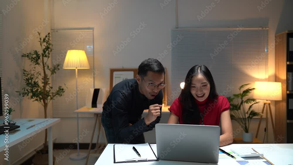 Two busy colleagues working together talking using laptop in office. Middle aged Asian fem, male worker looking at computer discussing business plan at office meeting. Two busy colleagues working together talking using laptop in office. Middle aged Asian fem, male worker looking at computer discussing business plan at office meeting.