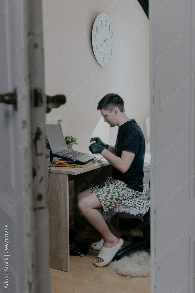 A young man puts stickers on a laptop keyboard. A young man puts stickers on a laptop keyboard.