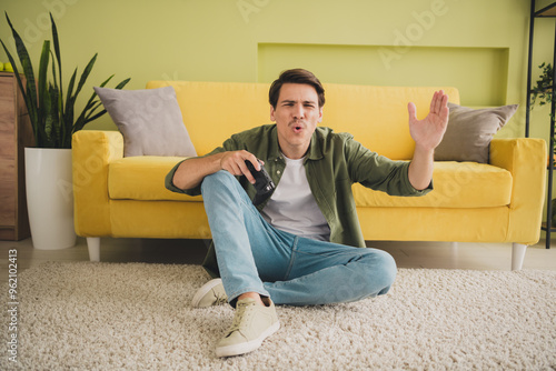 Photo of young attractive man sitting floor spending free time vacation modern interior home house indoors #962102413