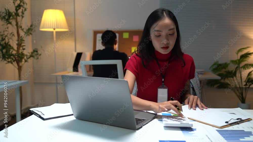 Two busy colleagues working together talking using laptop in office. Middle aged Asian fem, male worker looking at computer discussing business plan at office meeting. Two busy colleagues working together talking using laptop in office. Middle aged Asian fem, male worker looking at computer discussing business plan at office meeting.