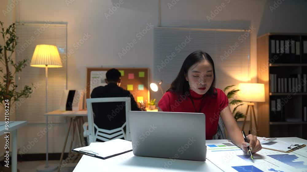 Two busy colleagues working together talking using laptop in office. Middle aged Asian fem, male worker looking at computer discussing business plan at office meeting. Two busy colleagues working together talking using laptop in office. Middle aged Asian fem, male worker looking at computer discussing business plan at office meeting.