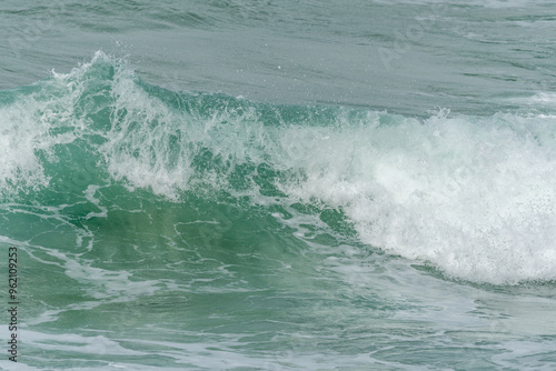 Wave of the green and blue Atlantic Ocean at the edge of a beach in the Iroise Sea.