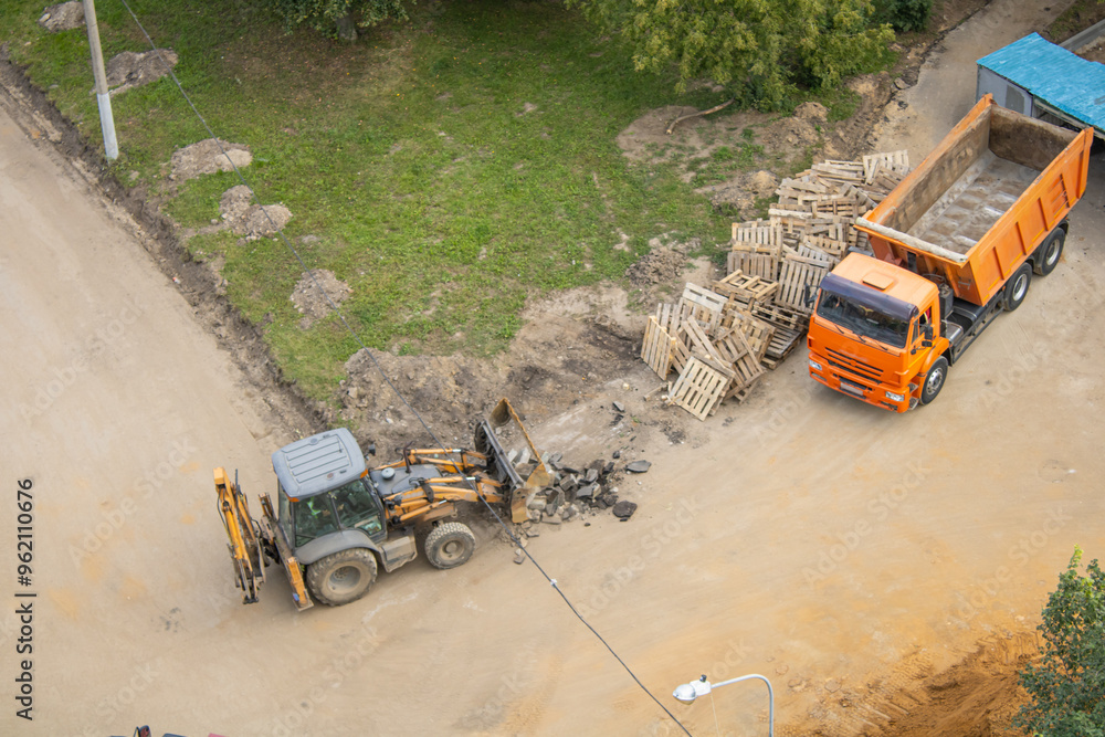 A bulldozer rakes asphalt into a pile, road works are underway A bulldozer rakes asphalt into a pile, road works are underway