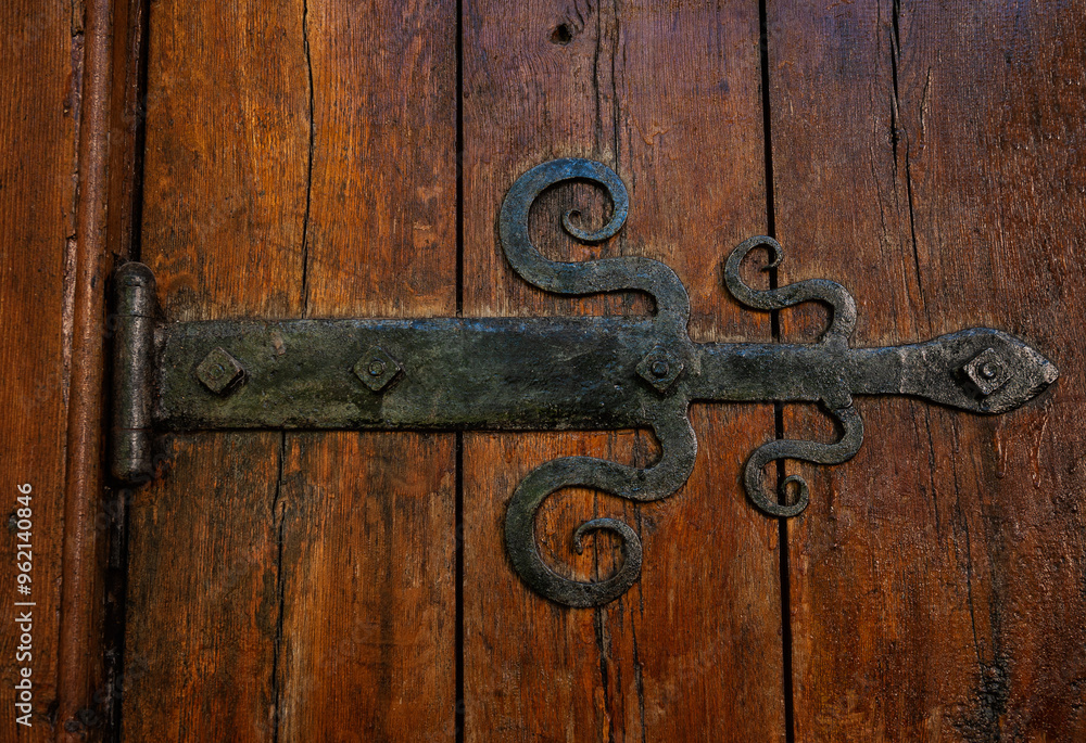 Antique iron hinge with a rusty patina on a wooden barn door Antique iron hinge with a rusty patina on a wooden barn door