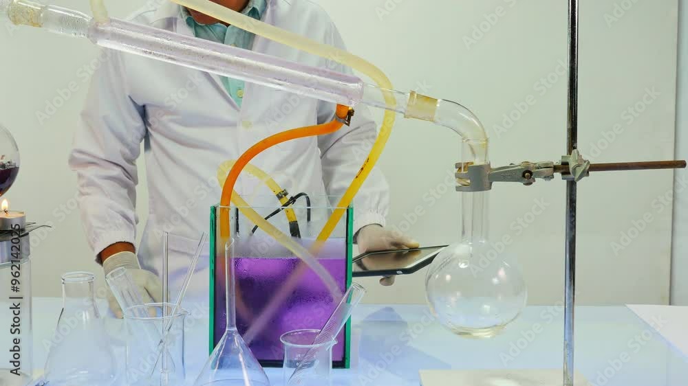 A laboratory scene showing a scientist operating a distillation apparatus. The setup includes various glassware, with a focus on the scientific process. The scientist is monitoring the experiment A laboratory scene showing a scientist operating a distillation apparatus. The setup includes various glassware, with a focus on the scientific process. The scientist is monitoring the experiment