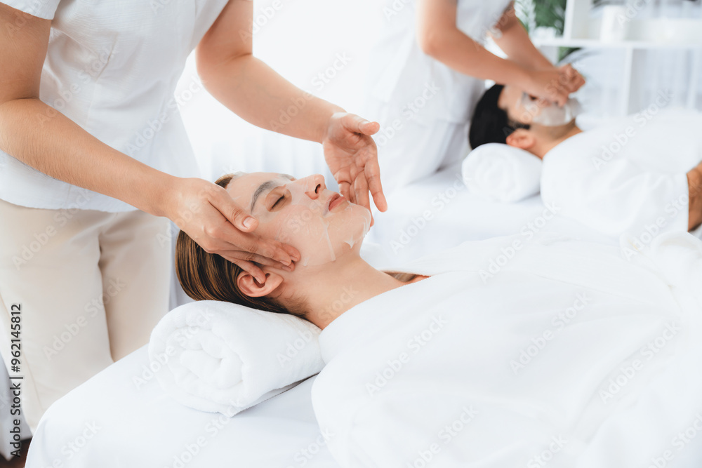 Obraz premium Serene modern daylight ambiance of spa salon, couple customer indulges in rejuvenating with facial skincare mask. Facial skin treatment and beauty cosmetology procedure for face. Quiescent