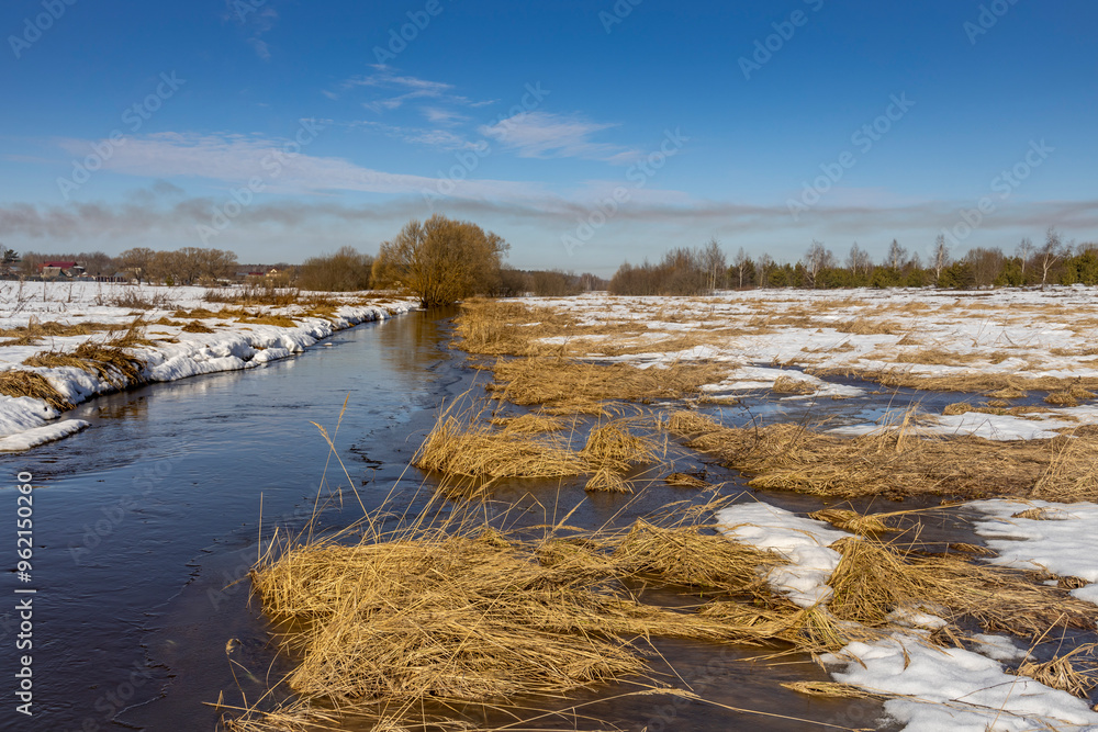 A field with a river running through it and a tree in the background A field with a river running through it and a tree in the background