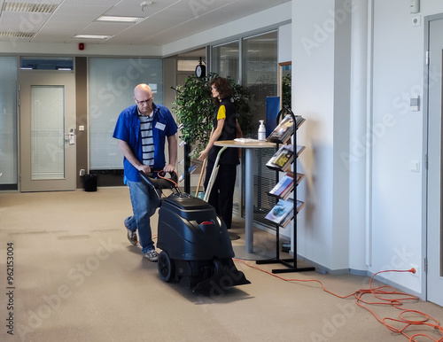 A Caucasian man washes carpet from stains using a Carpet washing machine.
