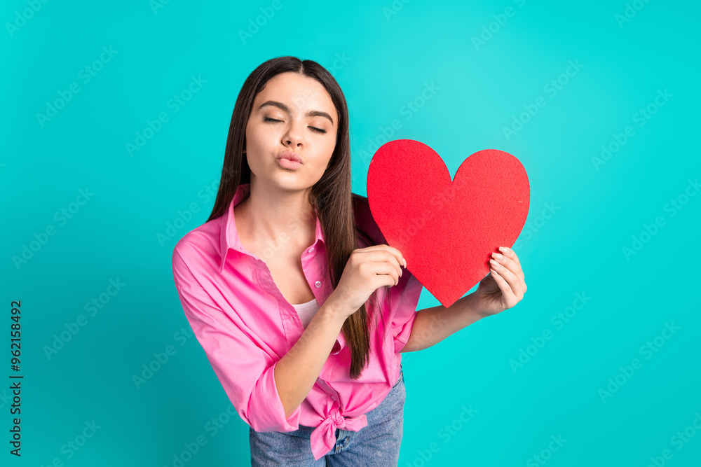 Photo portrait of attractive teen woman hold big heart postcard kissing lips dressed stylish pink clothes cyan on blue color background Photo portrait of attractive teen woman hold big heart postcard kissing lips dressed stylish pink clothes cyan on blue color background