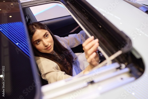 Konstfotografi Shot through opened car sunroof of young woman inspecting interior details of de