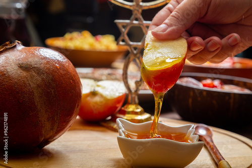 Tableau sur toile A woman's hand at the table during the Rosh Hashanah holiday dips an apple in ho