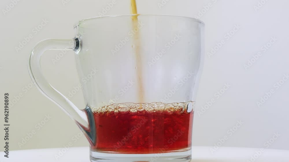 Strongly brewed tea is poured into a transparent mug in a thin stream. Medium shot. Strongly brewed tea is poured into a transparent mug in a thin stream. Medium shot.