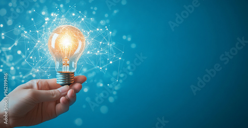 Hand holding a light bulb with a glowing effect and a network connection on a blue background