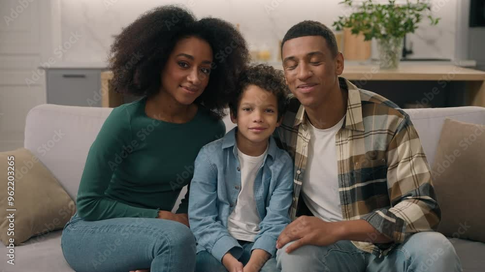 Cute loving African American ethnic happy family portrait parents woman man in love mother father little son boy child kid looking camera spouses homeowners posing together sit indoors home apartment Cute loving African American ethnic happy family portrait parents woman man in love mother father little son boy child kid looking camera spouses homeowners posing together sit indoors home apartment