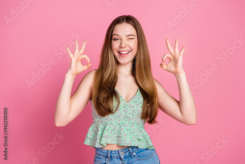 Portrait of nice young woman okey symbol eye wink wear singlet isolated on pink color background photo