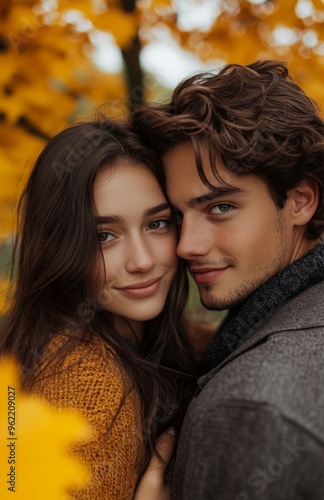 A loving young couple, man embracing girlfriend from behind, smiling in autumn park with yellow trees