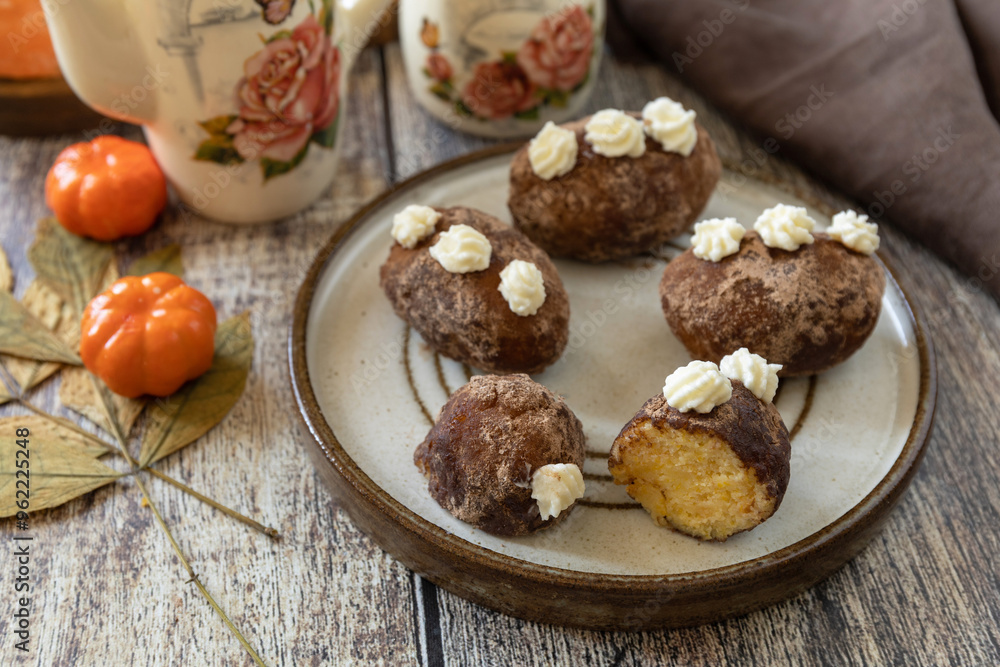 Fototapeta premium Chocolate rum potato cake with pumpkin on rustic background, homemade vegan dessert. Traditional Eastern European dish with cocoa and butter. Chocolate sweets filled with marzipan.