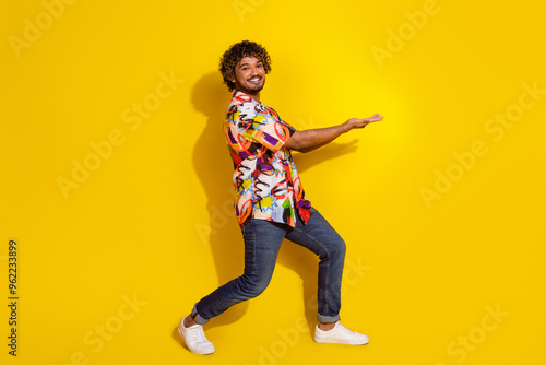 Full length portrait of nice young man hold empty space wear shirt isolated on yellow color background