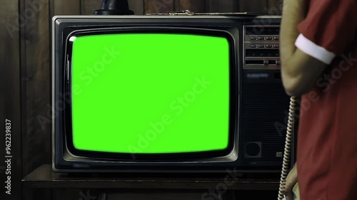 Man Holding 80s Phone While Turning On Old TV with Green Screen in a Dimly Lit Room - You Can Replace Green Screen with the Footage or Picture You Want with 'Keying' Effect (Check Out Tutorials) - 4K