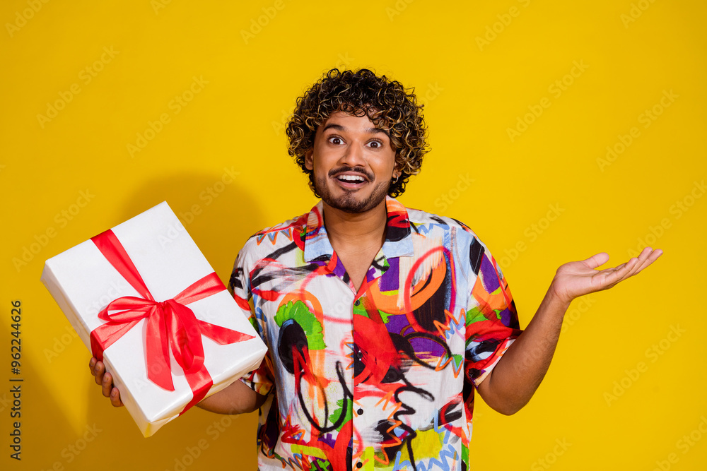 Photo portrait of attractive young man gift shrug shoulders shocked dressed stylish colorful clothes isolated on yellow color background Photo portrait of attractive young man gift shrug shoulders shocked dressed stylish colorful clothes isolated on yellow color background