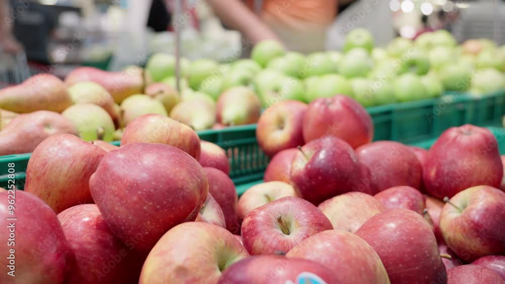 Red apples are beautifully arranged in supermarket, while customers select green apples in background, creating vibrant scene of grocery shopping and fresh produce choices Red apples are beautifully arranged in supermarket, while customers select green apples in background, creating vibrant scene of grocery shopping and fresh produce choices