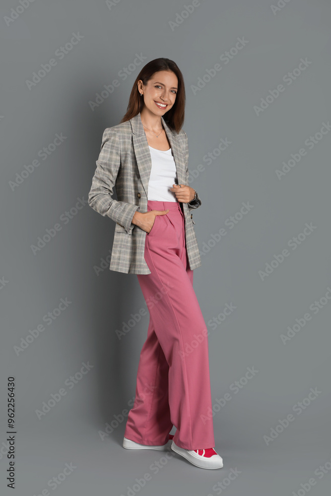 Beautiful woman in stylish jacket and pink pants on grey background Beautiful woman in stylish jacket and pink pants on grey background