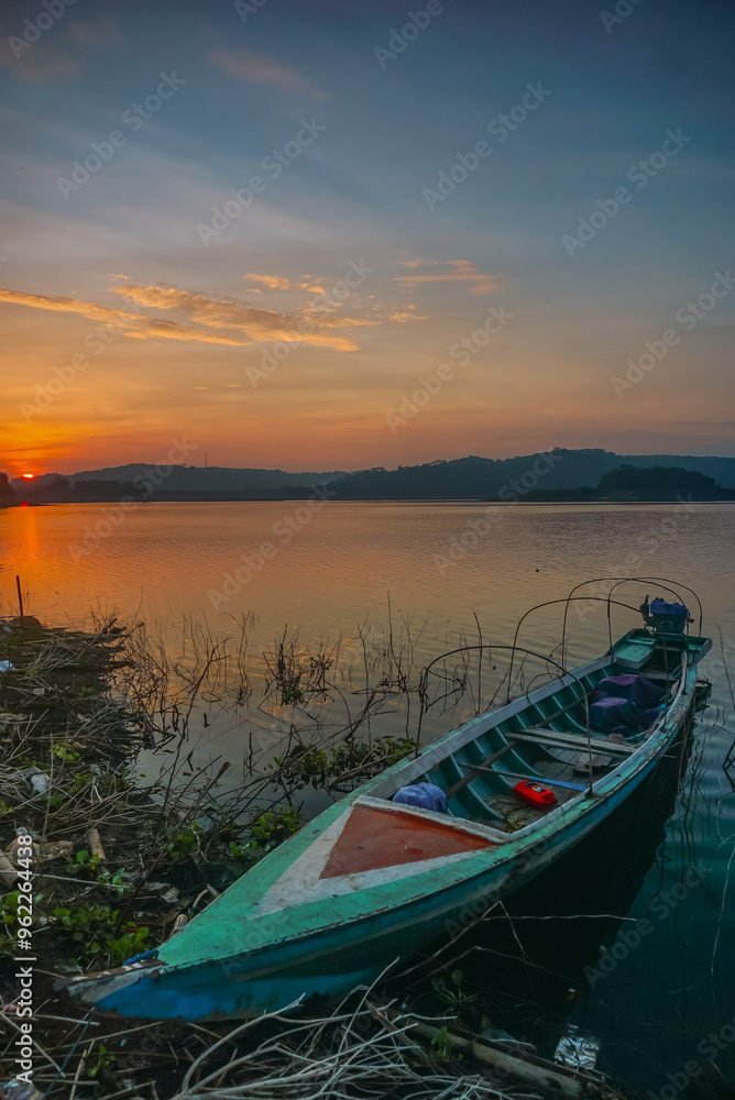 Lake boat at orange sunrise. Scenic sunrise background. Peaceful morning of Jatiluhur reservoir. Lake boat at orange sunrise. Scenic sunrise background. Peaceful morning of Jatiluhur reservoir.