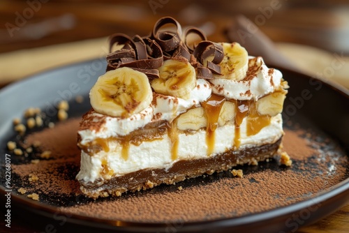 A slice of banoffee pie with layers of banana, cream, and caramel, garnished with chocolate curls photo