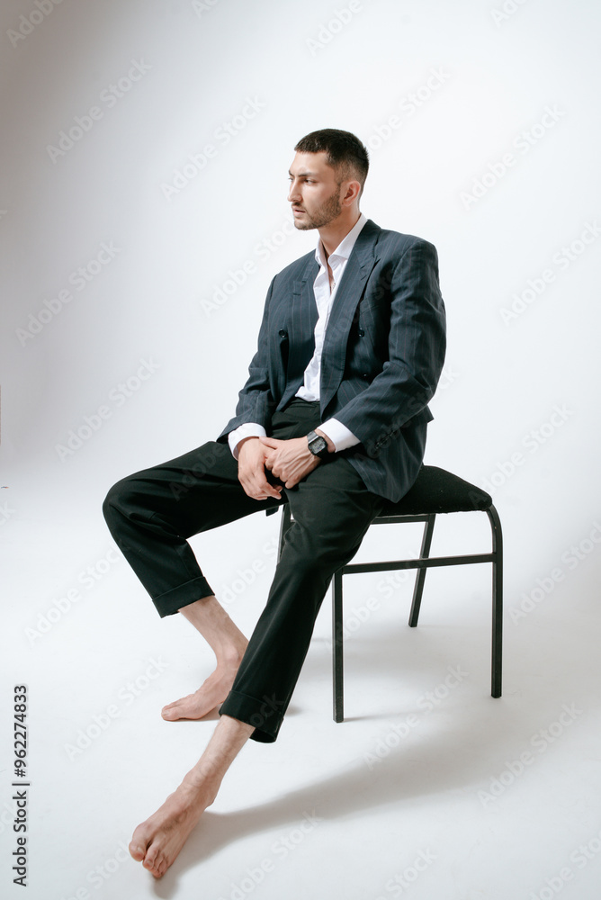 Handsome man, fashion model sits on chair, barefoot Handsome man, fashion model sits on chair, barefoot