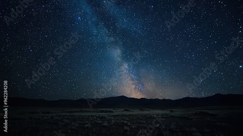   A stunning image of the night sky featuring the Milky Way with distant mountains and an abundance of sparkling stars