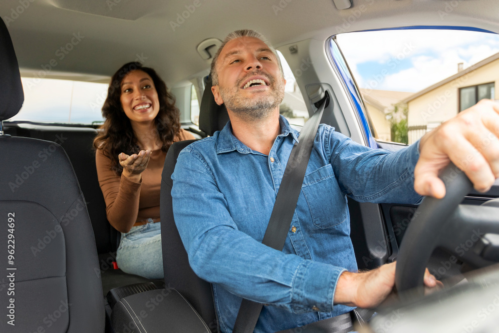 Positive woman passenger talking to cheerful taxi driver man, lady sitting on backseat. Easy transportation concept Positive woman passenger talking to cheerful taxi driver man, lady sitting on backseat. Easy transportation concept