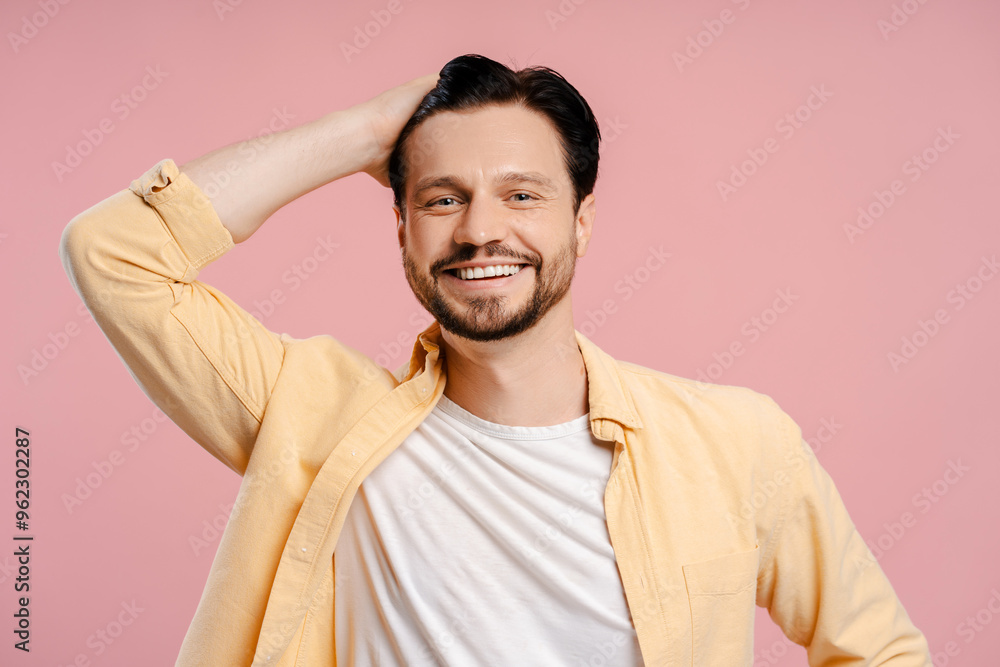 Handsome young, smiling man posing and touching his hair on pink background Handsome young, smiling man posing and touching his hair on pink background
