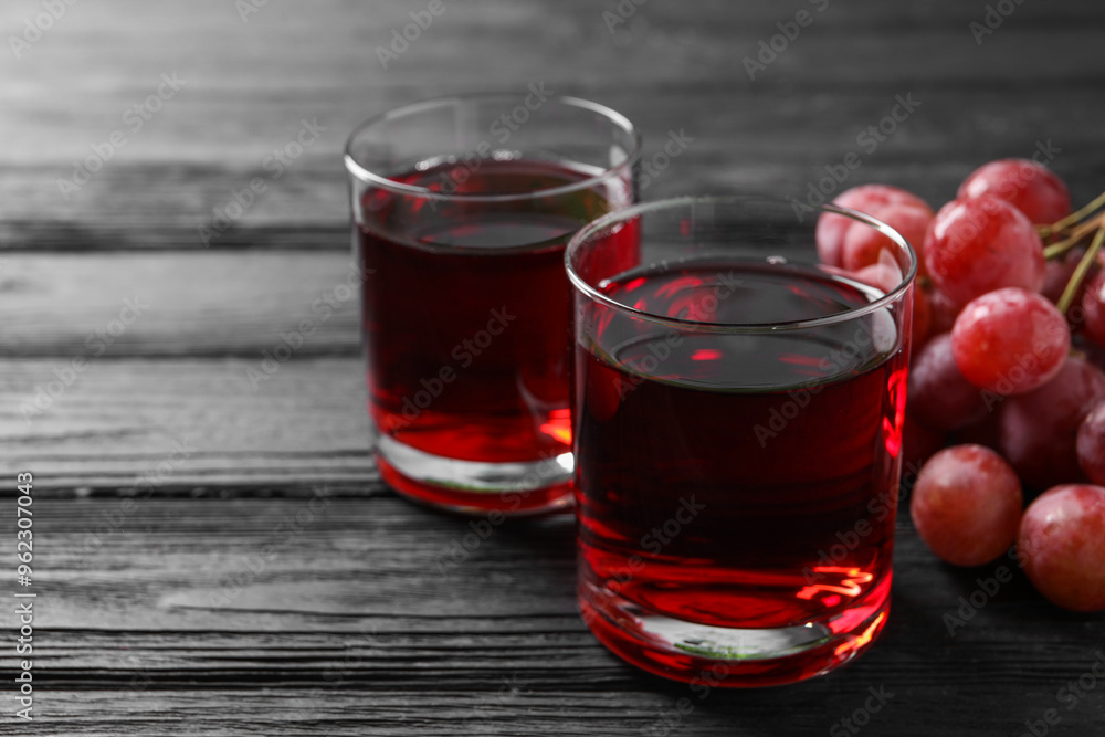 Tasty grape juice in glasses and berries on black wooden table, closeup Tasty grape juice in glasses and berries on black wooden table, closeup