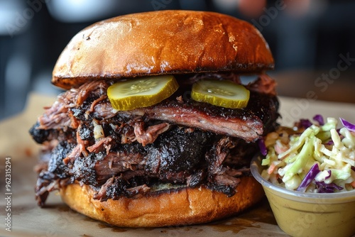 A smoked brisket sandwich served on a toasted bun with pickles and a side of coleslaw