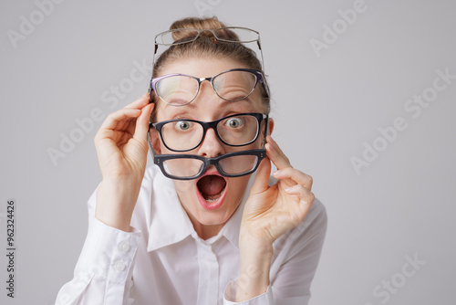 Εκτύπωση καμβά Surprised woman wearing multiple pairs of glasses with shocked expression, astig