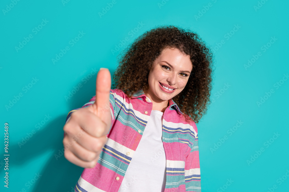 Photo of pretty young woman thumb up wear shirt isolated on teal color background Photo of pretty young woman thumb up wear shirt isolated on teal color background