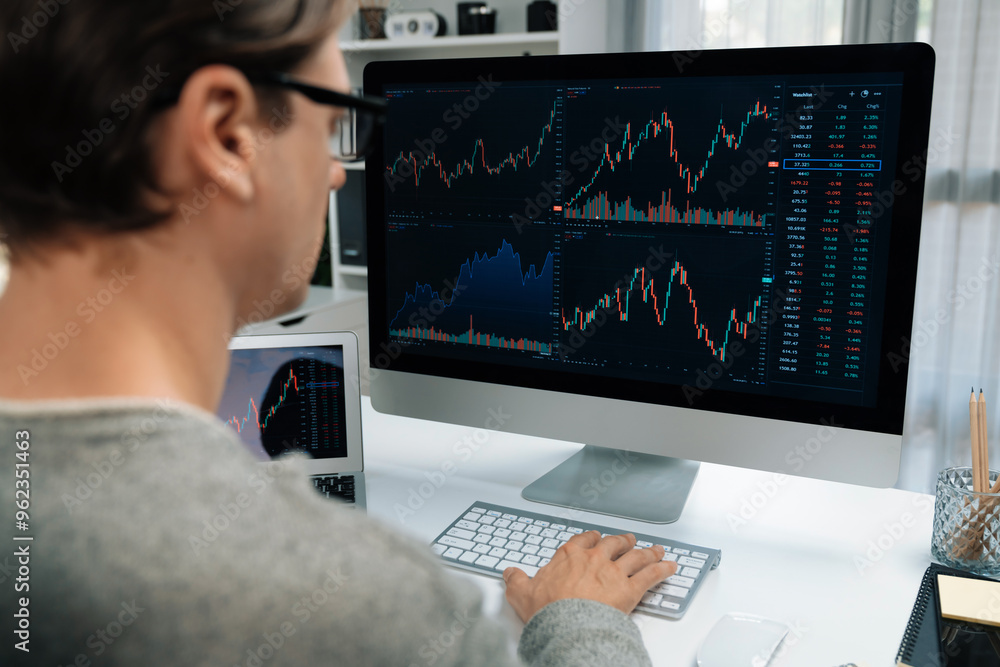 Business trader using computer and laptop to search highest profit value of dynamic increased stock market graph on working desk, analyzing exchange rate value on screen at modern office. Pecuniary. Business trader using computer and laptop to search highest profit value of dynamic increased stock market graph on working desk, analyzing exchange rate value on screen at modern office. Pecuniary.