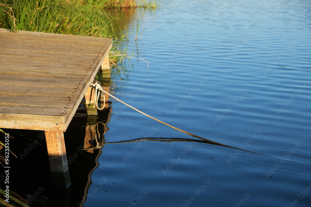 Obraz premium old pier over water, rope tied to pier, water striders on water