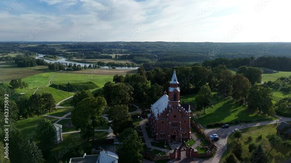 Aerial view of Kernave church and Neris river valley in Lithuania. Aerial view of the historic Kernave church with the Neris river valley in the background, surrounded by lush greenery in Lithuania. Aerial view of Kernave church and Neris river valley in Lithuania. Aerial view of the historic Kernave church with the Neris river valley in the background, surrounded by lush greenery in Lithuania.