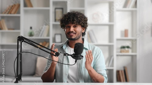 Microphone, podcast and Indian man speaker in his living room. Creative streamer, internet influencer or online content creator live streaming for audience. Camera view.