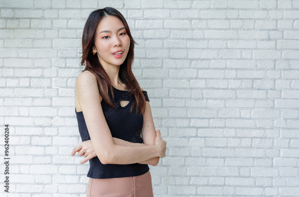 Confident Young Woman Standing with Arms Crossed Against White Brick Wall Confident Young Woman Standing with Arms Crossed Against White Brick Wall