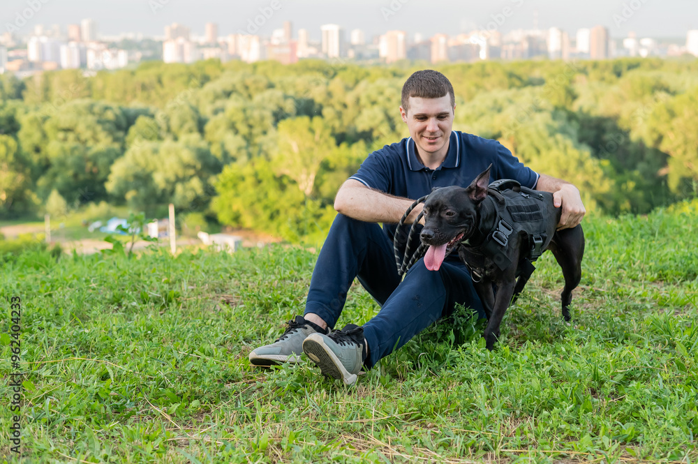 Caucasian man sitting with pit bull terrier on green lawn. Caucasian man sitting with pit bull terrier on green lawn.
