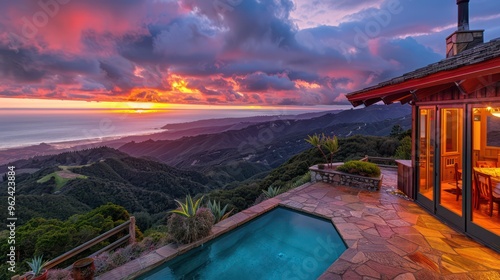 A stunning sunset view from a hillside home overlooking the ocean and mountains, with a pool in the foreground.