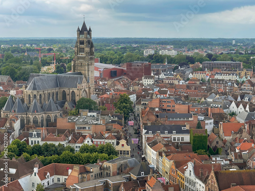 Brugge, Flanders, Belgium - June 22, 2024: Sint-Salvatorskathedraal and Steenstraat seen from Halletoren,, in urban jungle, cityscape of roofs and buildings under blue cloudscape photo