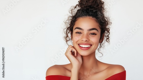 Portrait of a young woman with curly hair and a bright smile, wearing a red top.