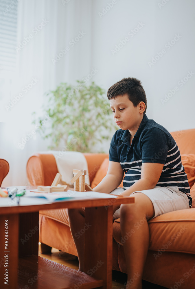 A young boy enjoys playing with wooden building blocks while sitting on the sofa in a cozy living room setting. A young boy enjoys playing with wooden building blocks while sitting on the sofa in a cozy living room setting.